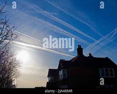 Leuchtender Morgenhimmel voller Kondensstreifen, gesehen über Sandford Village, südlich von Oxford. Stockfoto