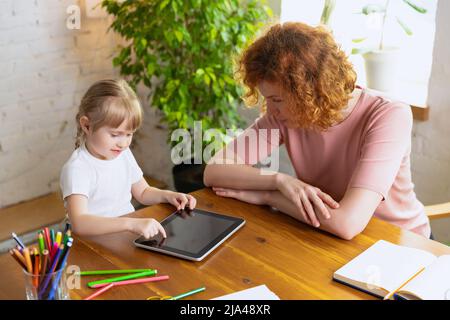 Einzelunterricht im Zentrum der frühen Entwicklung der Kinder. Professionelle Therapeutin kommuniziert mit dem Kind während außerschulischer Aktivitäten. Stockfoto