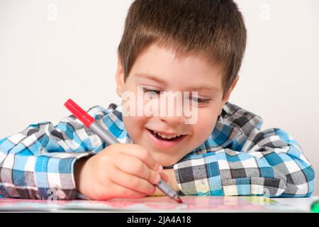 Ein Junge im Vorschulalter studiert und passiert Labyrinthe auf weißem Hintergrund. Vorbereitung für die Schule für Kinder. Stockfoto