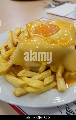 Traditionelles portugiesisches Sandwich mit Francesinha-Sauce auf dem Teller. Stockfoto