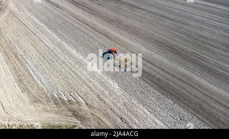 Traktor bereitet Feld im Frühjahr vor. Drohnenansicht. Stockfoto