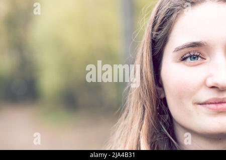 Nahaufnahme Aufnahme eines wunderschönen braunen blonden Teenagers vor einem natürlichen grünen Hintergrund mit Kopierfläche. Hochwertige Fotos Stockfoto