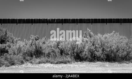 Ein Feldweg verläuft entlang eines Abschnitts der US-mexikanischen Grenzmauer in der Nähe von Fabens, Texas und östlich von El Paso. Stockfoto