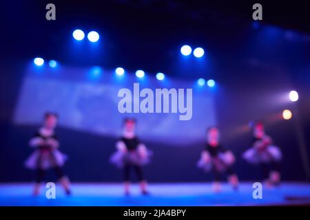 Ein verschwommener abstrakter Hintergrund eines Tanzfestivals von einer Gruppe von Mädchen in der Anzahl von vier Personen. Helle Beleuchtung der blauen Tanzfläche. Hochwertige Fotos Stockfoto