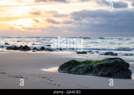 Sanfter, dramatischer Sonnenuntergang mit dunklen Wolken im Hintergrund mit Fokus auf einem großen Felsen an einer leicht felsigen Küste in Frankreich, Cap Blanc-Nez. Hochwertige Fotos Stockfoto