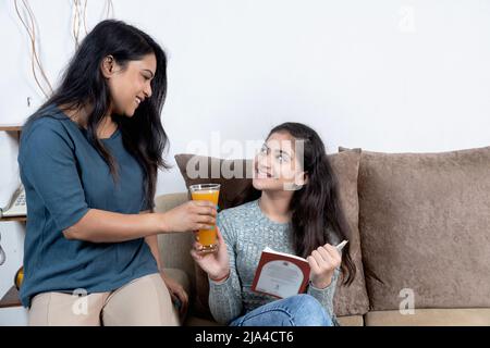 indische Mutter, die Tochter, Mutter und Tochter ein Glas Saft gab Stockfoto