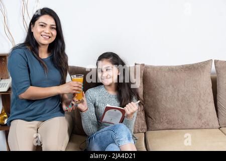 indische Mutter, die Tochter, Mutter und Tochter ein Glas Saft gab Stockfoto