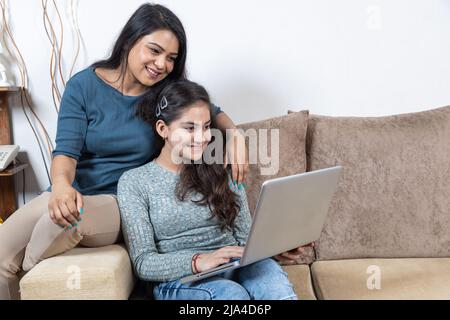 Glückliche Mutter und Tochter beim Blick auf den Laptop Stockfoto