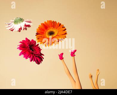 Kreatives Arrangement mit verschiedenen Frühlingsblumen und Puppenbeinen in High Heels auf pastellbeigem Hintergrund. Minimales Federkonzept. Stockfoto