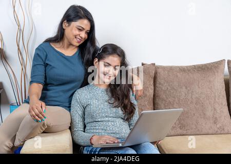 Glückliche Mutter und Tochter beim Blick auf den Laptop Stockfoto