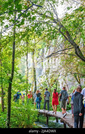 Plitvicer Seen, Kroatien - 3. September 2018: Nationalpark Plitvicer Seen, ein Wunder der Natur, Touristen, die auf der Holzbrücke spazieren Stockfoto