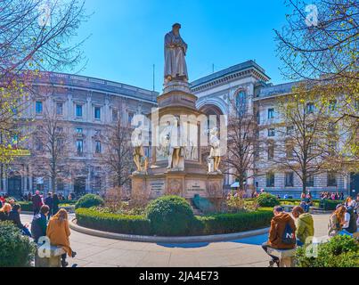 MAILAND, ITALIEN - 5. APRIL 2022: Am 5. April in Mailand, Italien, ruhen sich die Menschen in einem Park auf der Piazza della Scala um die Skulptur von Leonardo da Vinci herum Stockfoto