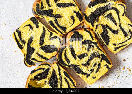 Ungewöhnliches Kürbis-Marmorbrot (Tiger-Print) mit Tintenfischfarbe, geflochten auf hellem Hintergrund. Nützliche Backwaren. Stockfoto