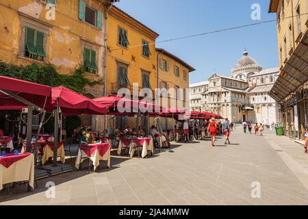 Touristen und Restaurants im Freien in der Innenstadt von Pisa, im Hintergrund die Kathedrale Santa Maria Assunta, Piazza dei Miracoli, Toskana, Italien, Europa. Stockfoto