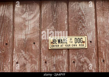 Vorsicht vor dem Hundeschild an einem Holzzaun. Stockfoto