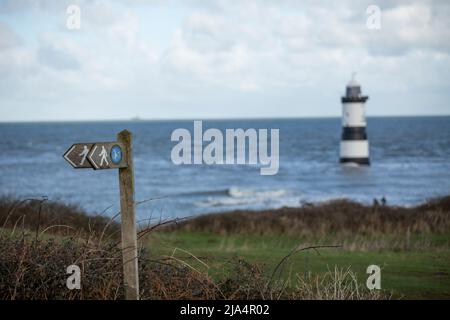 Hölzerne walisische Küstenweg Schild mit trwyn du Leuchtturm im Hintergrund Stockfoto