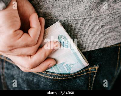 Seine Hand russische Rubel in Jeans Tasche oder Jackentasche Stockfoto