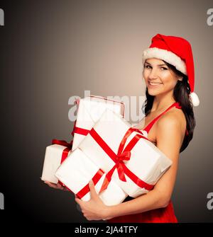 Weihnachtsmütze Weihnachten Frau hält weihnachtsgeschenke lächelnd glücklich und aufgeregt. Nette schöne multi-rassische kaukasische asiatische santa Mädchen auf schwarz isoliert Stockfoto