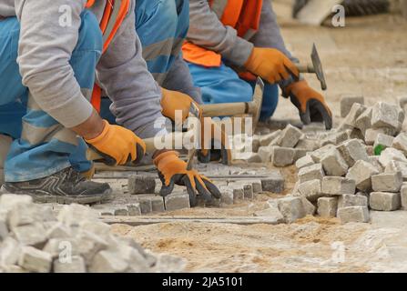 Pflastersteine legen und einen neuen Bürgersteig in der Stadt schaffen. Prag, Tschechische Republik. Menschen mit Körperteilen. Stockfoto