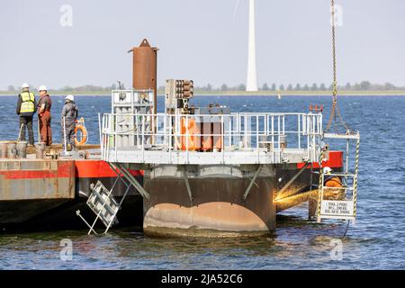 Lelystad, Niederlande - 22. April 2022: Arbeiter mit Schneidbrenner bei der Arbeit von Abbruchfundament Offshore-Windturbine Stockfoto