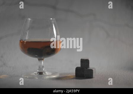 Transparenter Whiskey auf grauem Hintergrund. Whiskey-Steine im Glas Stockfoto