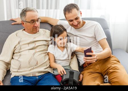 Großvater und Enkelin, Vater mit Smartphone zu Hause Stockfoto