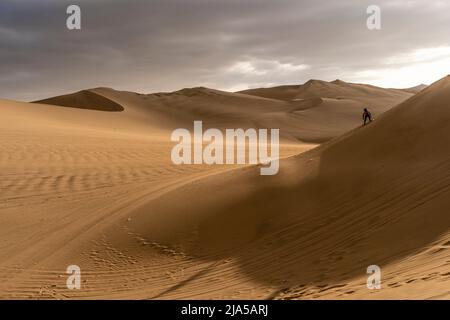 Ein Mann Sandboarding auf den Sanddünen von Huacachina, Provinz Ica, Peru. Stockfoto