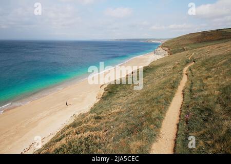 Einfarbiger Hundespaziergang an einem Sandstrand in Cornwall mit blauem und türkisfarbenem Meer Stockfoto