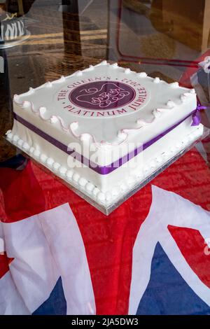 Die „Platinum Jubilee 2022“-Torte der Königin wurde in einem Kuchenfenster auf einem mit der „Union Jack“-Flagge bedeckten Tisch in Surrey, England, Großbritannien, gezeigt Stockfoto