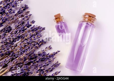 Ätherisches Lavendelöl in Glasflaschen für Spa oder violette oder violette Farbe mit rustikalen frischen Lavendelblüten Stockfoto