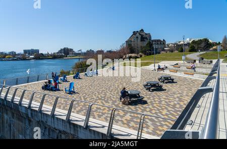 Victoria, BC, Kanada - 14 2021. April : West Bridge Plaza Festival Park. Neu umgebaues Rastgebiet der Johnson Street Bridge. Adirondack-Stühle für Touristen. Stockfoto