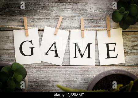 Eine Reihe von gedruckten Karten, die das WORTSPIEL auf einem alten hölzernen Hintergrund schreiben. Stockfoto