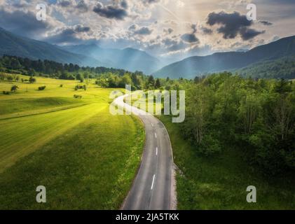Luftaufnahme der Straße in grünen Wiesen und hils bei Sonnenuntergang im Sommer Stockfoto
