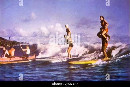 Vintage-Farbpostkartenbild von Tandem-Surfen und Outrigger-Kanufahren am Waikiki Beach in Honolulu, Hawaii, c1950s. Stockfoto