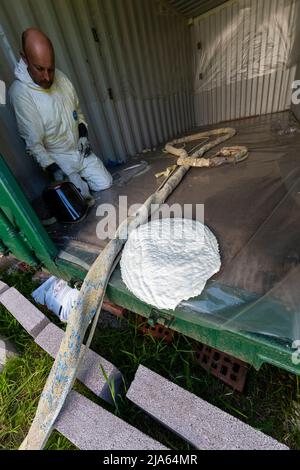 Ein Arbeiter sprüht eine Transportbehälterdecke mit Grapho Therm, um die Ansammlung von Kondenswasser zu verhindern. Stockfoto