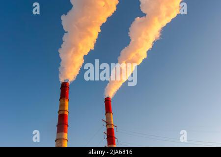Weißer Rauch kommt aus den Rohren am blauen Himmel Stockfoto