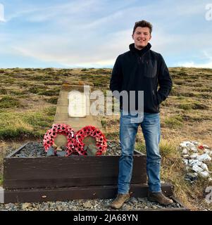 Der Enkel von LT Col Jones, PA Media Reporter Henry Jones, steht neben einer Gedenkstätte für LT Col H Jones. Oberstleutnant Herbert 'H' Jones VC, der während der Schlacht um Goose Green am 28 1982. Mai in einem entscheidenden Moment des Falklandkrieges auf argentinischer Position getötet wurde. Einer von 255 britischen Soldaten, die während des Konflikts ums Leben kamen, der Kommandeur des Bataillons 2., Parachute Regiment, wurde für seine Taten mit dem Victoria Cross ausgezeichnet, der höchsten und renommiertesten Auszeichnung des britischen Ehrensystems. LT Col Jones' Enkel, PA Media Reporter Henry Jones, reflektiert über die Stockfoto