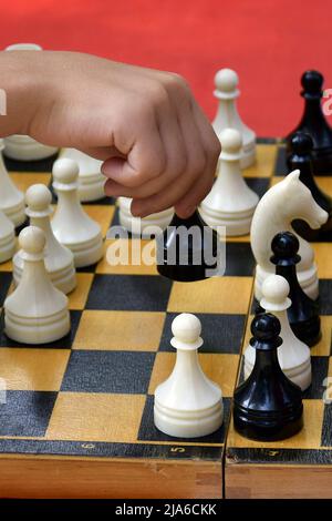 Die Hand des Spielers bewegt ein Stück auf einem Schachbrett. Schachspiel. Figur verschieben. Figur verschieben. Nahaufnahme. Selektiver Fokus. Stockfoto