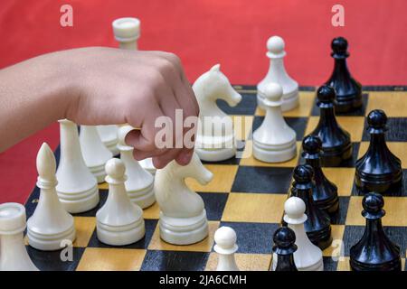 Die Hand des jungen Spielers bewegt ein Stück auf einem Schachbrett. Schachspiel. Figur verschieben. Nahaufnahme. Stockfoto