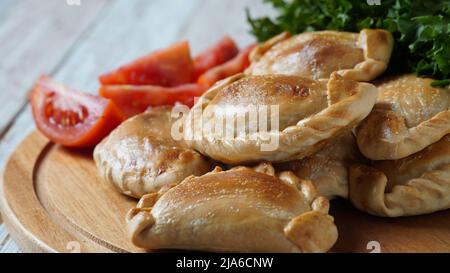 Lateinamerikanische gebratene Empanadas mit Tomatensauce. Argentinische Empanada ist ein Gebäck Umsatz mit einer Vielzahl von herzhaften Zutaten gefüllt und gebacken oder f Stockfoto