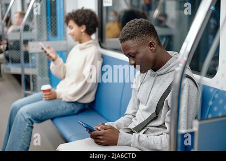 Junge Menschen mit Smartphones reisen in der U-Bahn . Stockfoto