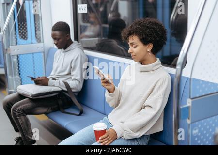 U-Bahn-Passagiere, die ihr Smartphone benutzen, während sie im c Stockfoto