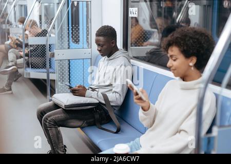 Junge Menschen mit Smartphones reisen in der U-Bahn . Stockfoto