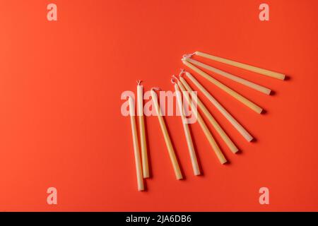 Festliche Komposition mit traditionellen jüdischen Kerzen für den Chanukka-Feiertag auf rotem Hintergrund, Draufsicht. Alte Rituale. Stockfoto