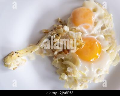 Draufsicht auf fryingwhite Teller mit zwei Eiern auf gerösteten onionthat Menschen in der Ukraine oft kochen gebraten Stockfoto