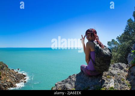 Frau Trekker sitzt auf dem Gipfel des Berges über dem Meer Stockfoto