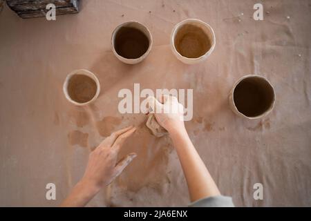 Kleine Töpferei Geschäft, handgemachte Prozess der Modellierung und Bildhauerei ein Tonglas in einer Werkstatt. Handwerker Hände und Tonvasen Stockfoto