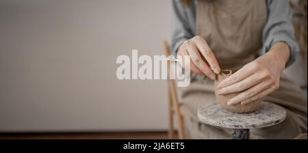 Nahaufnahme von weiblichen Händen, die mit Ton arbeiten. Der Töpfer macht Geschirr und andere Bastelarbeiten. Keramik. Hobby- und Freizeitkonzept, Stockfoto