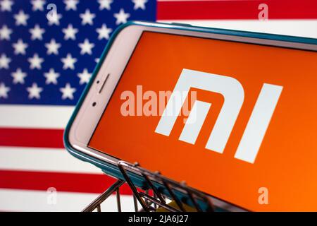 Kumamoto, JAPAN - Feb 31 2021 : das Logo von Xiaomi, dem chinesischen Elektronikunternehmen, macht und investiert in Smartphones, Apps usw. auf dem iPhone mit US-Flagge bg. Stockfoto