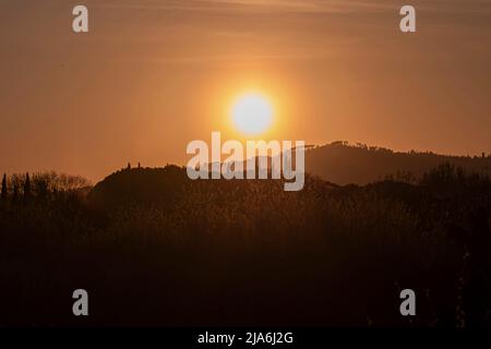 Sonnenuntergang in den toskanischen Hügeln in Italien, warme Orangentöne Stockfoto